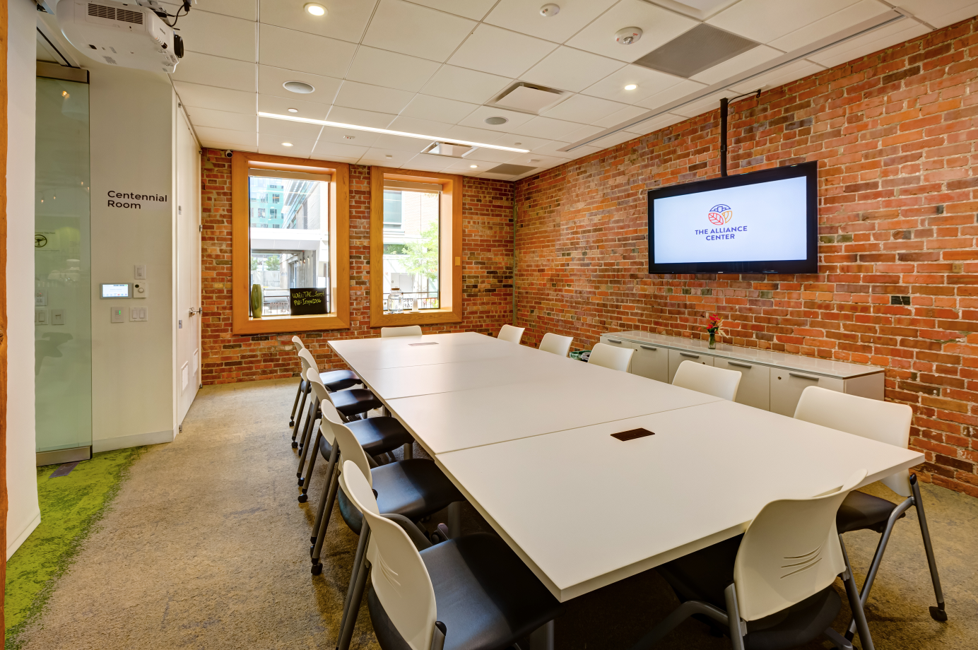 Alliance Center meeting room with large board table and wall mounted screen.