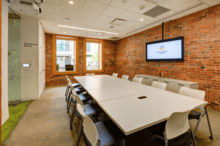 Alliance Center meeting room with large board table and wall mounted screen.